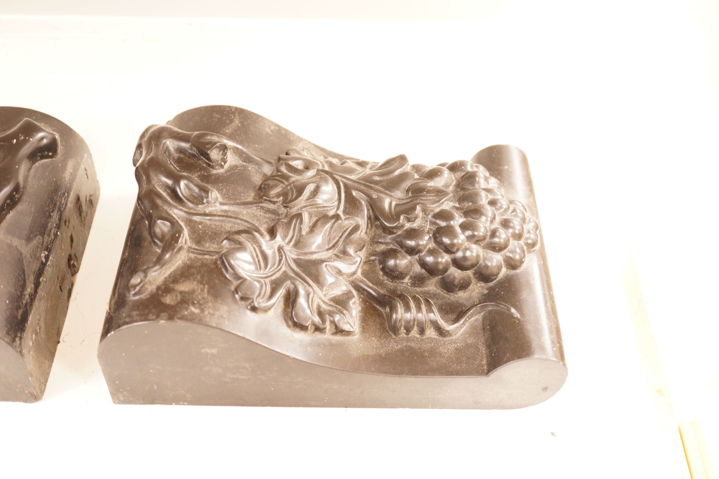 A pair of carved black marble corbels, fruiting vines, 24x17cm
